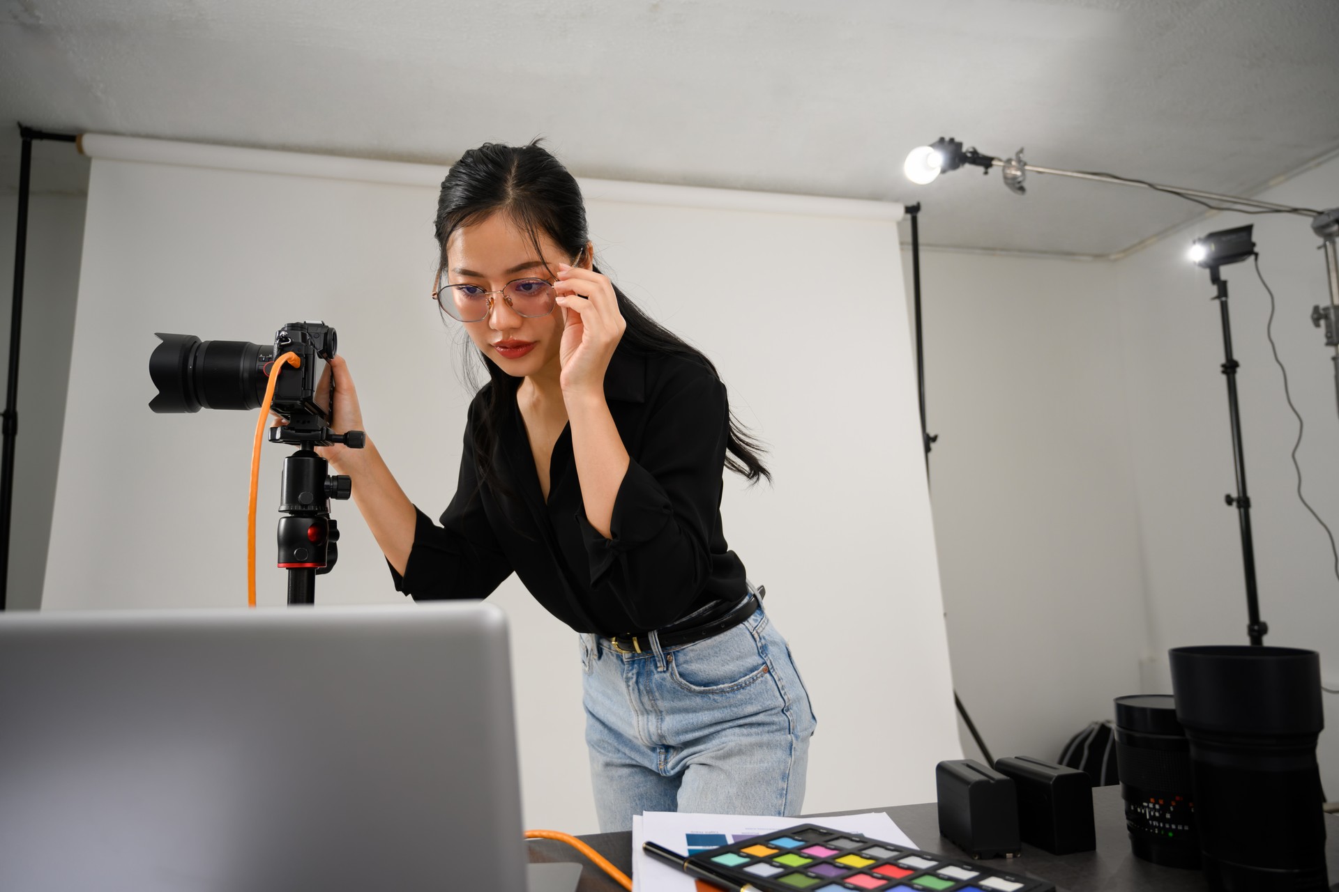 Female photographer holding professional camera and checking photos in laptop